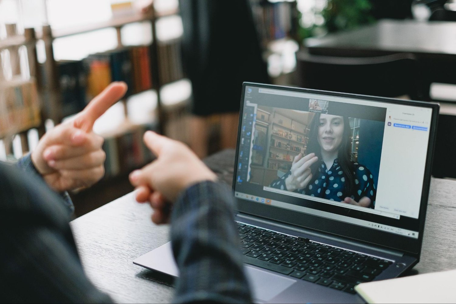 a person on a laptop video call is gesturing to a person off-camera
