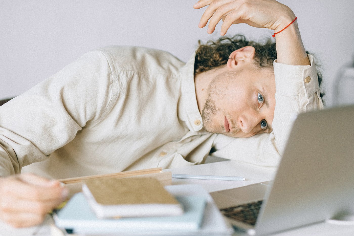 a man is sitting at his desk with his head resting on his arm, he looks tired and overwhelmed
